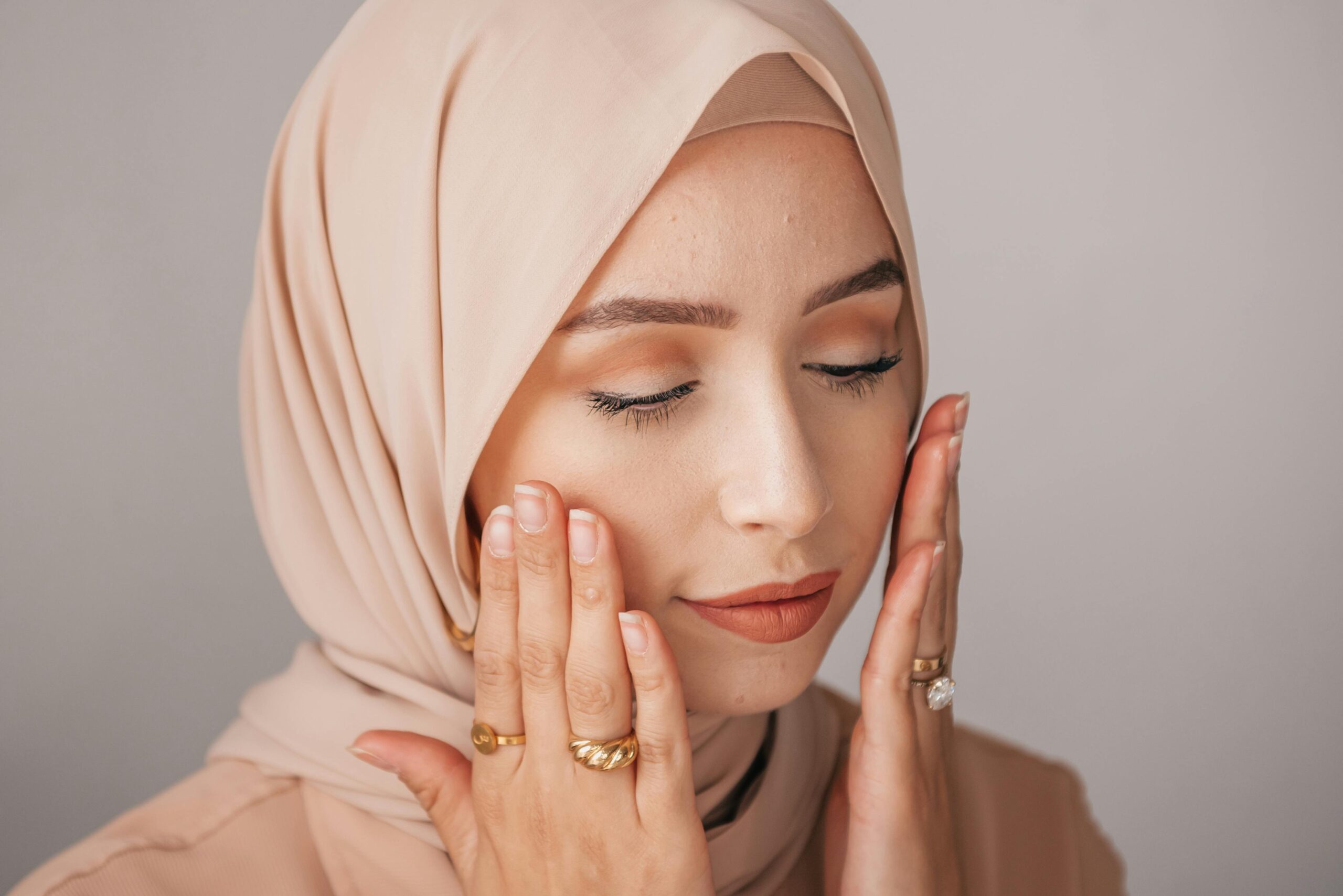 Portrait of a serene woman in hijab with soft natural makeup, showcasing elegance and tranquility.